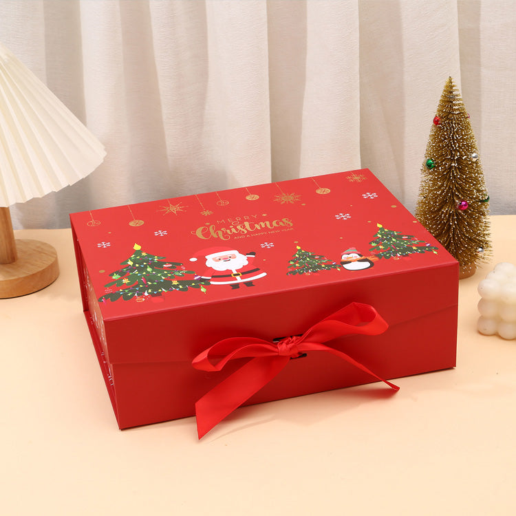 Red Christmas-themed gift box with a bow on a beige surface.