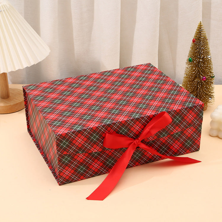 Rectangular gift box wrapped in red and green plaid paper with a red ribbon, on a neutral background.