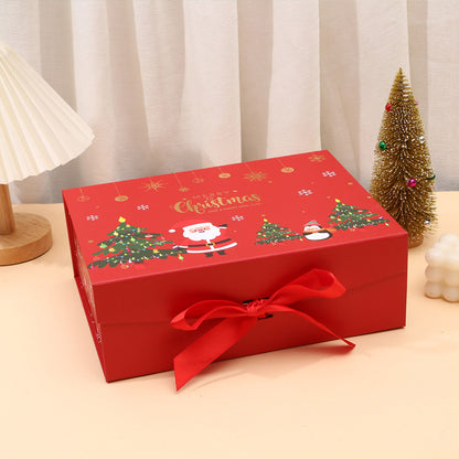 Red Christmas-themed gift box with a bow on a beige surface.